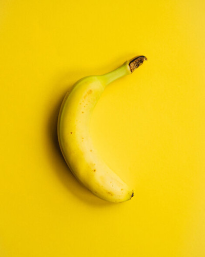Yellow Banana - Tapet cu un design modern si minimalist, prezentand o banana galbena pe un fundal galben.