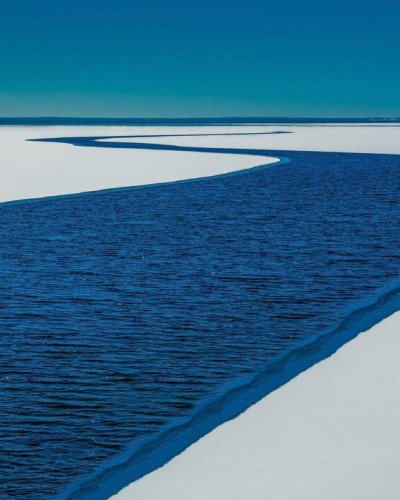 Tapet foto cu un râu albastru care se varsă intr-un lac albastru, pe un fundal alb.