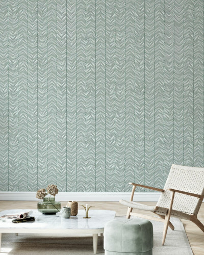 Tapet Herringbone Green în living, cu canapea gri și scaun din răchită.
