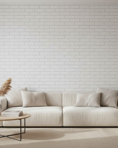 Un living modern și luminos cu un perete acoperit cu tapet Chalk Loft Brick personalizat, prezentând o textură de cărămidă albă. În cameră se află o canapea bej, o masă de cafea rotundă din lemn cu picioare metalice și o lampă de podea, creând o atmosferă