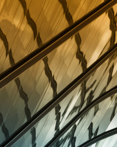 Fototapet abstract Patterned Lineage Study - personalizat, cu design arhitectural auriu-turcoaz într-un living modern, cu canapea bej și măsuță de cafea.