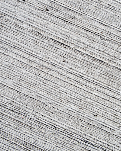 Hol modern cu tapet texturat Urban Grit Canvas gri, oglindă rotundă aurie, consolă minimalistă neagră și plantă de interior verde. Design urban-chic.