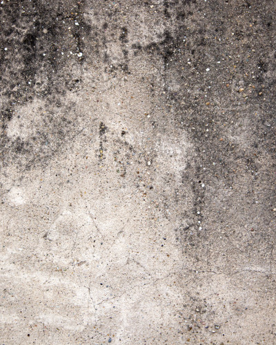 Tapet industrial cu textură de beton, gri-negru, instalat pe perete într-un hol modern cu consolă neagră, vază decorativă, oglindă mare și covor de iută.