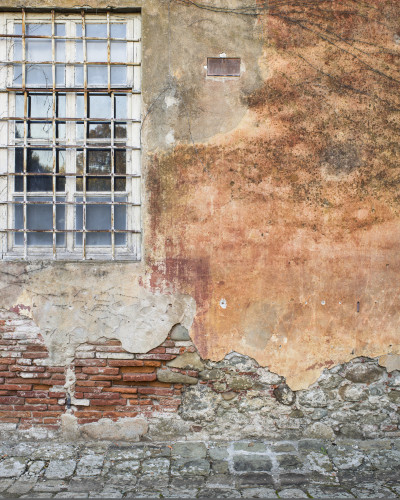 Fototapet Broken Window Grayscale - personalizat, montat pe un perete. Prezintă un design de zid vechi, deteriorat, cu cărămizi expuse și o fereastră industrială cu grilaj, într-un interior modern cu consolă neagră și decorațiuni.