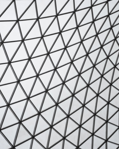 Perete decorat cu tapet geometric Urban Glass Facets într-un restaurant modern, cu lumini calde și mese aranjate elegant.